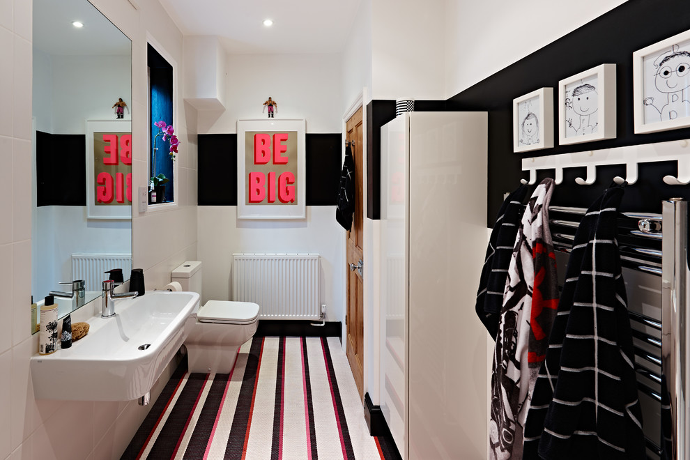 Exemple d'une petite salle de bain tendance pour enfant avec un placard à porte plane, des portes de placard blanches, un mur noir, un lavabo suspendu et un sol multicolore.