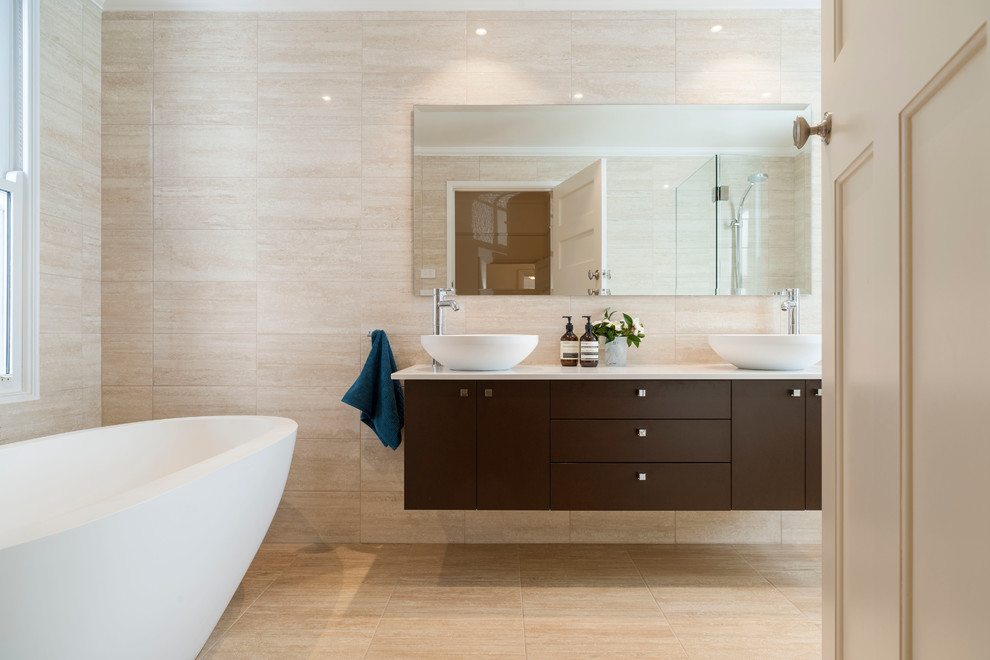 Inspiration for a small contemporary ensuite bathroom in Melbourne with a vessel sink, flat-panel cabinets, dark wood cabinets, marble worktops, a freestanding bath, a walk-in shower, a two-piece toilet, beige tiles, beige walls and porcelain flooring.