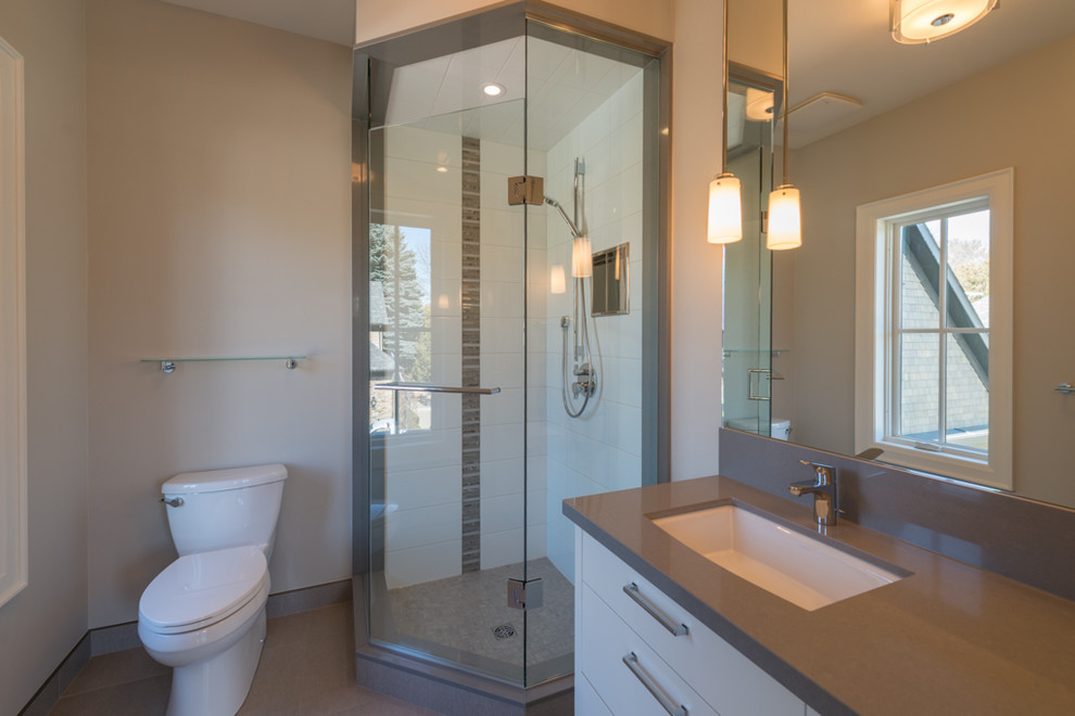Photo of a contemporary family bathroom in Toronto with a submerged sink, flat-panel cabinets, white cabinets, solid surface worktops, a corner shower, a two-piece toilet, grey tiles, porcelain tiles, grey walls and porcelain flooring.