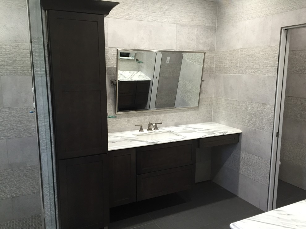 Inspiration pour une salle de bain principale minimaliste en bois foncé de taille moyenne avec un placard à porte shaker, une douche ouverte, un carrelage gris, un carrelage de pierre, un mur gris, un sol en vinyl, un lavabo encastré et un plan de toilette en marbre.