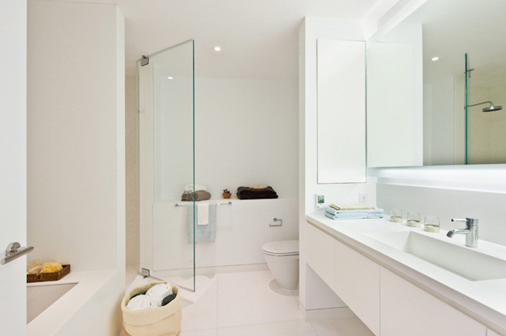 Modernes Badezimmer mit integriertem Waschbecken, flächenbündigen Schrankfronten, weißen Schränken, weißen Fliesen und weißem Boden in New York