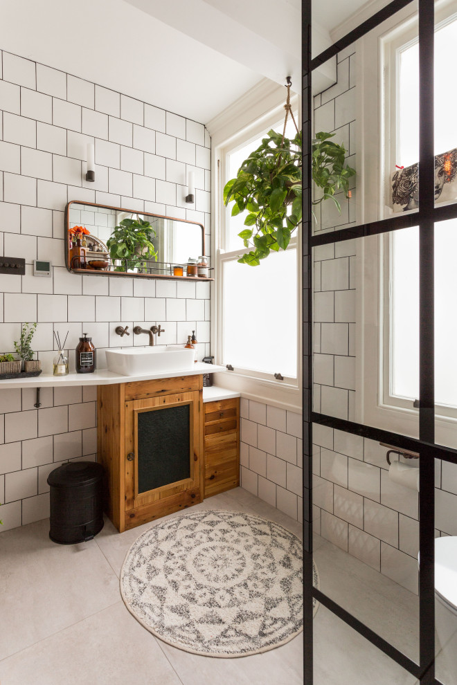 Inspiration for a transitional white tile gray floor bathroom remodel in Sussex with recessed-panel cabinets, medium tone wood cabinets, a vessel sink and white countertops