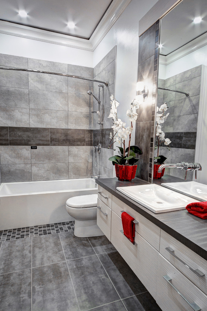 Inspiration for a small contemporary bathroom in Ottawa with a built-in sink, flat-panel cabinets, laminate worktops, an alcove bath, a one-piece toilet, grey tiles, ceramic tiles, grey walls, ceramic flooring and white cabinets.