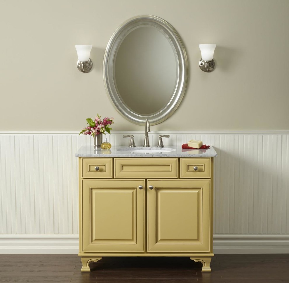 Inredning av ett klassiskt mellanstort en-suite badrum, med luckor med upphöjd panel, gula skåp, beige väggar, mörkt trägolv, ett undermonterad handfat, marmorbänkskiva och brunt golv