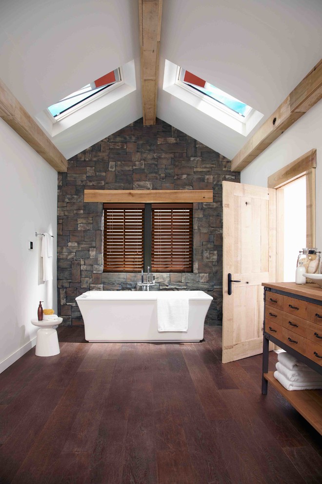 Inredning av ett lantligt mellanstort brun brunt en-suite badrum, med skåp i mellenmörkt trä, träbänkskiva, ett fristående badkar, vita väggar, mörkt trägolv, ett fristående handfat och släta luckor