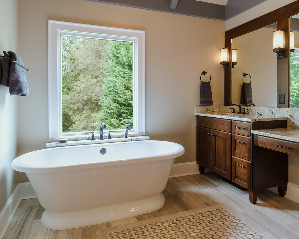 Immagine di una stanza da bagno classica con ante in stile shaker, ante in legno bruno, vasca freestanding e piastrelle beige