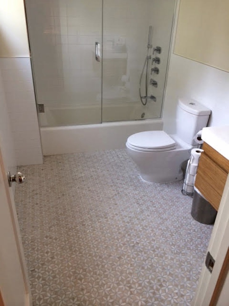 Klassisk inredning av ett mellanstort badrum med dusch, med släta luckor, beige skåp, ett badkar i en alkov, en dusch/badkar-kombination, en toalettstol med hel cisternkåpa, vit kakel, porslinskakel, beige väggar, mosaikgolv, ett integrerad handfat, bänkskiva i akrylsten, beiget golv och dusch med gångjärnsdörr