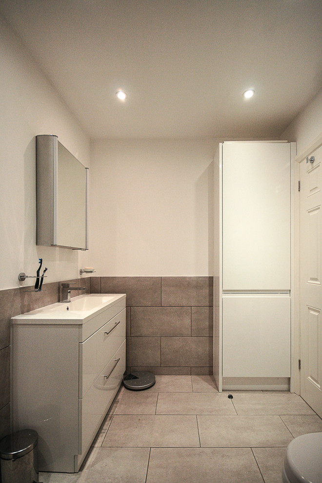 Medium sized contemporary family bathroom in London with flat-panel cabinets, white cabinets, a built-in bath, a shower/bath combination, a one-piece toilet, beige tiles, porcelain tiles, white walls, porcelain flooring, an integrated sink and engineered stone worktops.