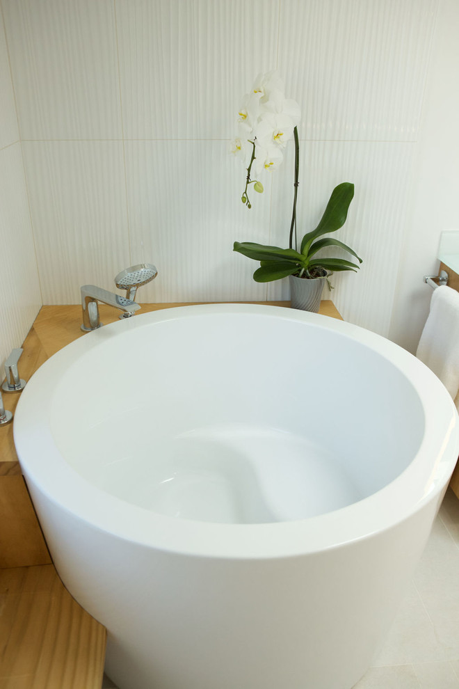 Идея дизайна: большая главная ванная комната в современном стиле с плоскими фасадами, светлыми деревянными фасадами, японской ванной, душем без бортиков, унитазом-моноблоком, белой плиткой, керамической плиткой, белыми стенами, полом из керамической плитки, монолитной раковиной, столешницей из переработанного стекла, белым полом, шторкой для ванной и белой столешницей