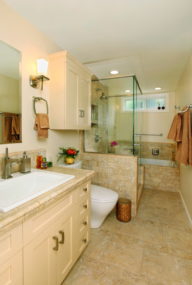 Medium sized traditional bathroom in Los Angeles with shaker cabinets, beige cabinets, an alcove bath, a one-piece toilet, porcelain tiles, beige walls, limestone flooring, a built-in sink, limestone worktops, beige floors and a hinged door.