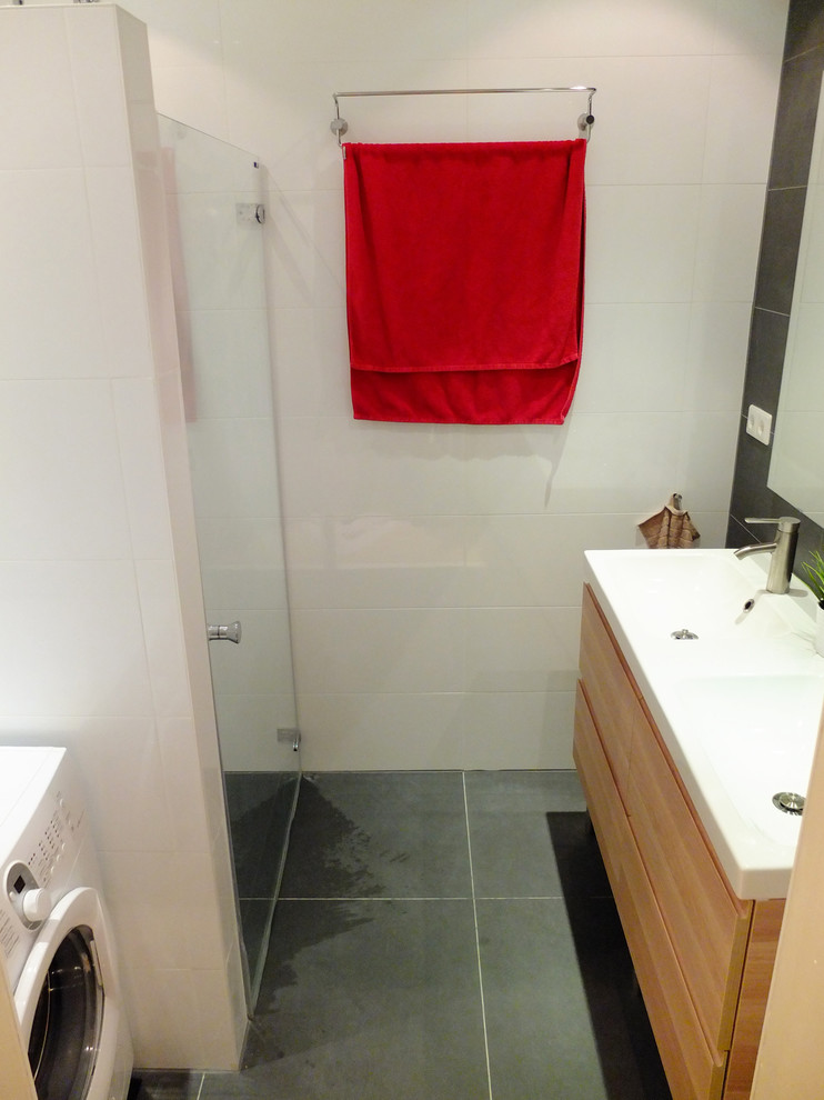 Inredning av ett modernt litet badrum, med ett konsol handfat, släta luckor, skåp i mellenmörkt trä, en kantlös dusch, flerfärgad kakel, keramikplattor, grå väggar och klinkergolv i keramik