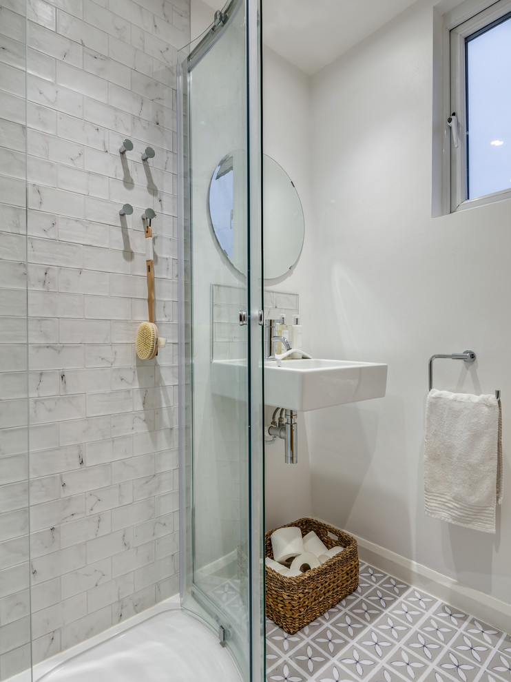 Immagine di una piccola stanza da bagno moderna con doccia ad angolo, piastrelle bianche, pareti gialle, pavimento con piastrelle in ceramica, lavabo sospeso, pavimento bianco e porta doccia scorrevole