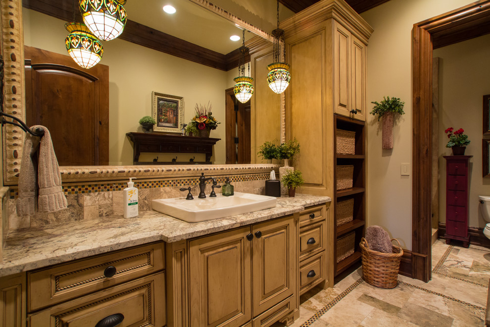 Mediterranean bathroom in Salt Lake City with a built-in sink, raised-panel cabinets, beige tiles and yellow cabinets.