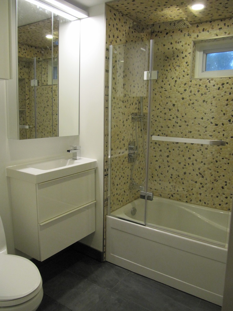 Пример оригинального дизайна: маленькая ванная комната в стиле модернизм с плоскими фасадами, белыми фасадами, ванной в нише, душем над ванной, унитазом-моноблоком, бежевой плиткой, галечной плиткой, белыми стенами, полом из керамогранита, душевой кабиной, монолитной раковиной, столешницей из искусственного камня, серым полом, душем с распашными дверями и белой столешницей для на участке и в саду