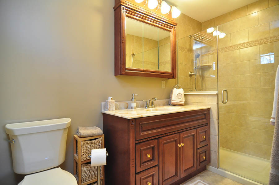Idéer för att renovera ett litet vintage badrum, med bruna skåp, en toalettstol med separat cisternkåpa, beige kakel, keramikplattor, beige väggar, klinkergolv i keramik, ett integrerad handfat, bänkskiva i onyx, beiget golv och dusch med gångjärnsdörr