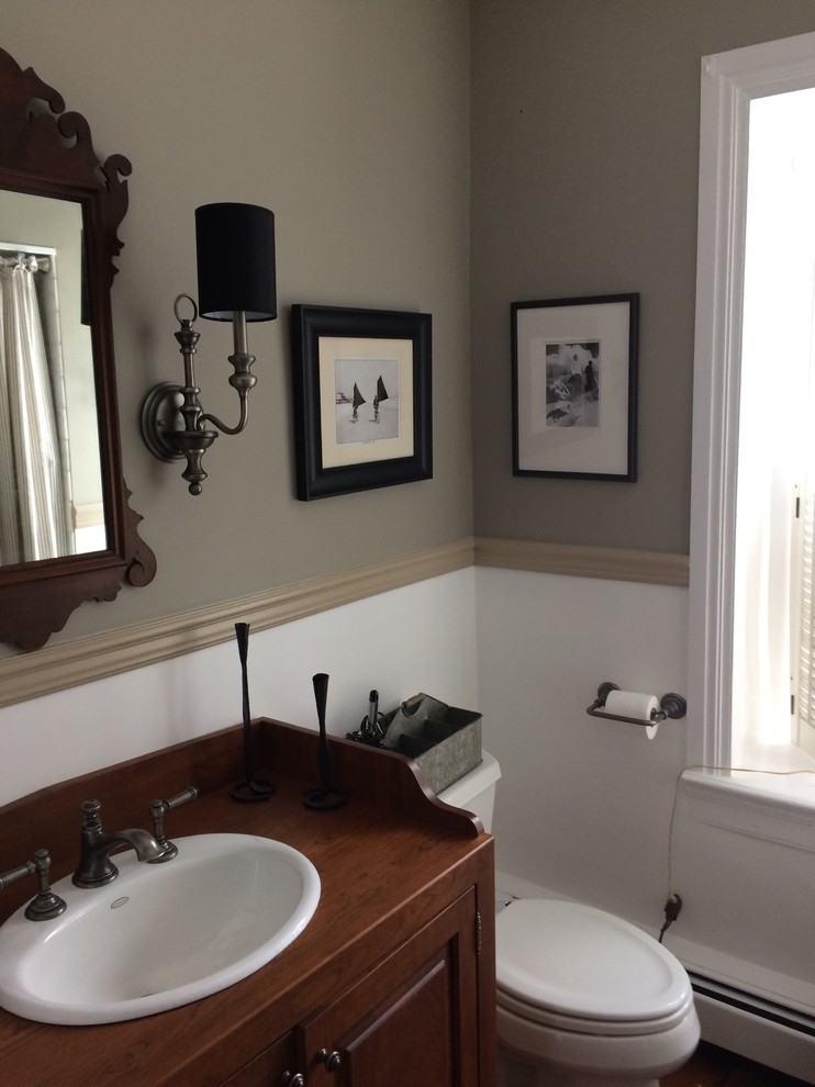 Bild på ett litet vintage brun brunt badrum med dusch, med luckor med upphöjd panel, skåp i mörkt trä, en dusch i en alkov, en toalettstol med separat cisternkåpa, vit kakel, stenkakel, grå väggar, mörkt trägolv, ett nedsänkt handfat, träbänkskiva, ett badkar i en alkov, brunt golv och dusch med duschdraperi
