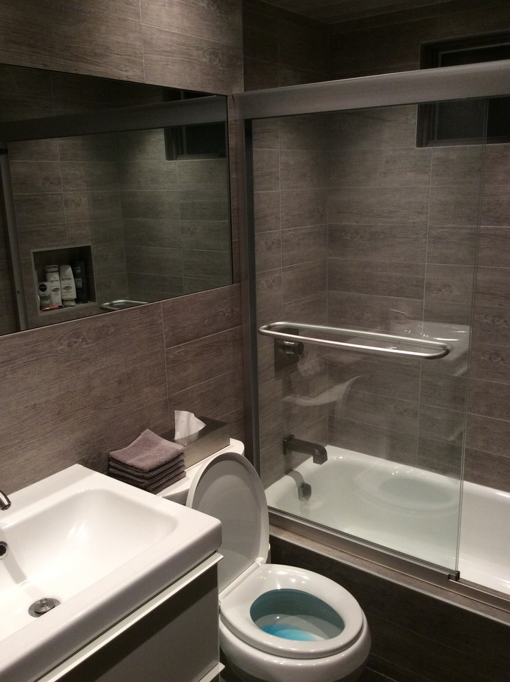 Modelo de cuarto de baño minimalista de tamaño medio con puertas de armario grises, combinación de ducha y bañera, baldosas y/o azulejos grises, baldosas y/o azulejos de vidrio laminado, paredes marrones, suelo de pizarra y lavabo integrado