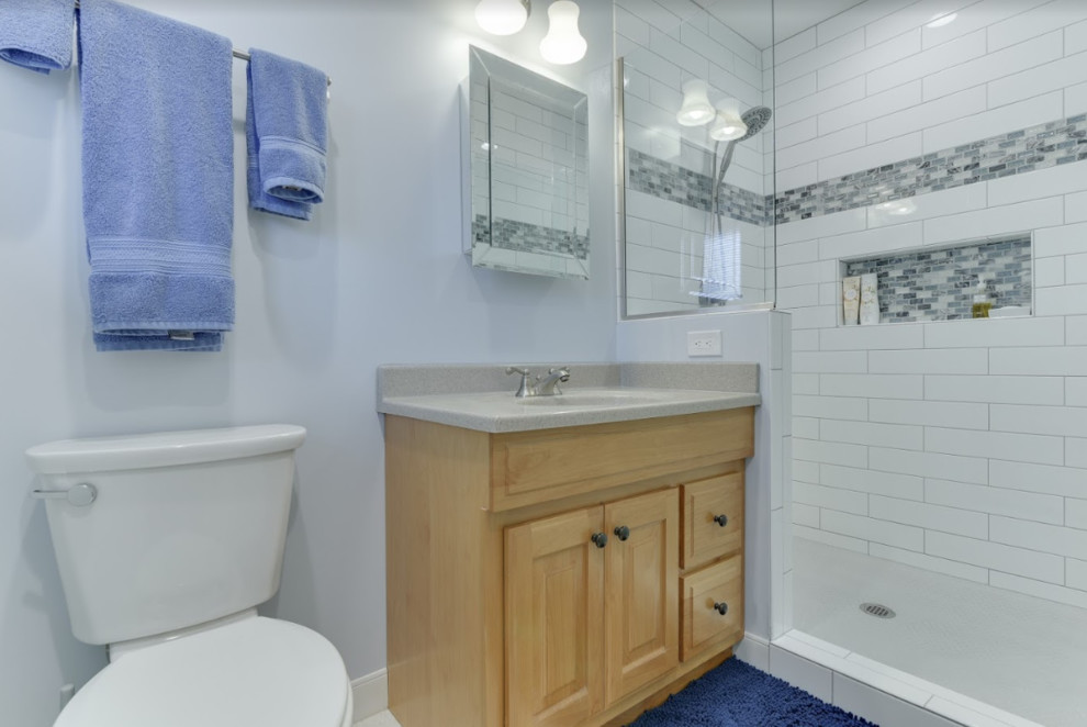 Photo of a medium sized classic family bathroom in Portland with shaker cabinets, a one-piece toilet, white tiles, metro tiles, grey walls, porcelain flooring, engineered stone worktops, white floors, white worktops, an alcove shower, an integrated sink, a hinged door and light wood cabinets.