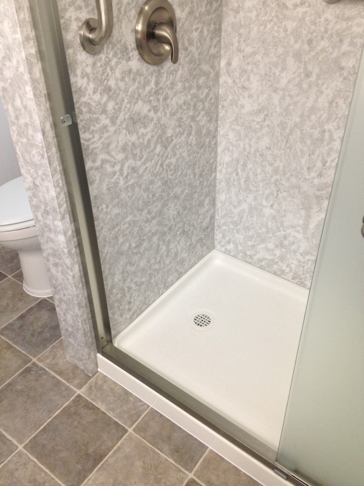 This is an example of a medium sized traditional ensuite bathroom in Cleveland with raised-panel cabinets, white cabinets, an alcove shower, a two-piece toilet, blue tiles, grey walls, vinyl flooring, an integrated sink, marble worktops, grey floors, a sliding door and white worktops.