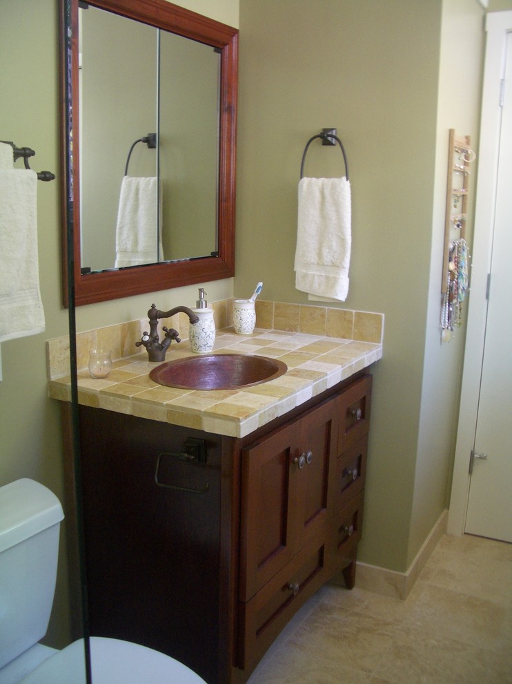 Example of a small classic 3/4 beige tile and stone tile travertine floor alcove shower design in Orange County with shaker cabinets, dark wood cabinets, a two-piece toilet, green walls, a drop-in sink and tile countertops