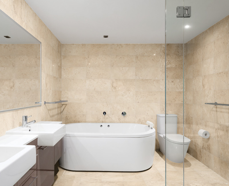 Réalisation d'une grande salle de bain principale design avec un placard à porte plane, des portes de placard marrons, une baignoire indépendante, une douche d'angle, WC à poser, un carrelage beige, du carrelage en marbre, un mur beige, un sol en marbre, une vasque et un sol beige.