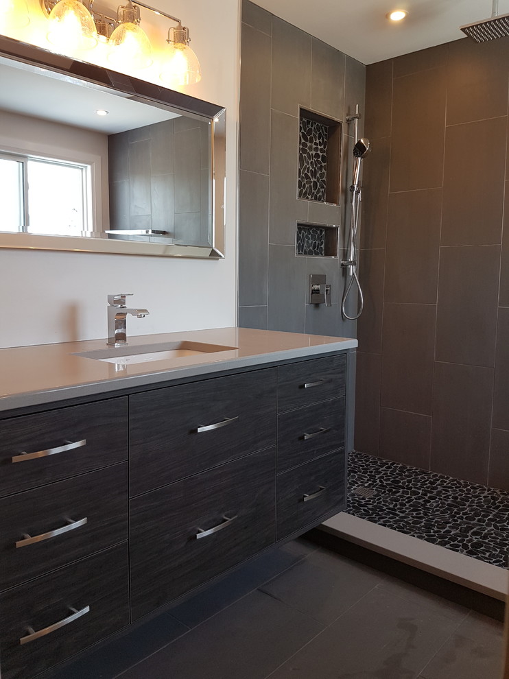 Modern inredning av ett mellanstort grå grått badrum med dusch, med släta luckor, svarta skåp, en hörndusch, grå kakel, porslinskakel, vita väggar, korkgolv, ett undermonterad handfat, bänkskiva i akrylsten, grått golv och med dusch som är öppen