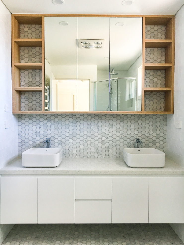 На фото: главная ванная комната в современном стиле с стеклянными фасадами, белыми фасадами и столешницей из искусственного кварца с