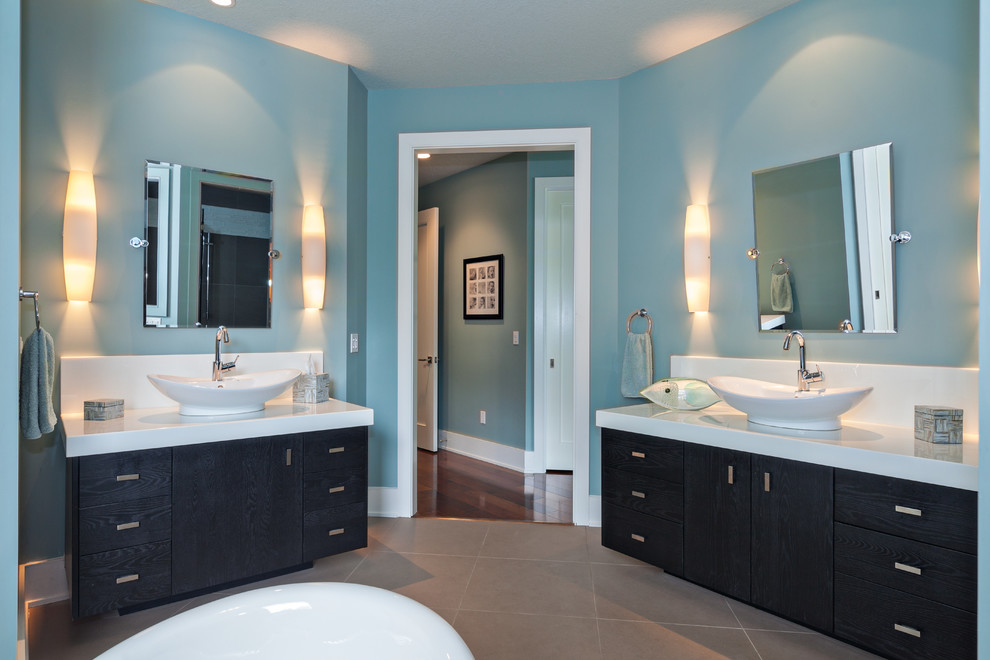Esempio di una stanza da bagno padronale tradizionale di medie dimensioni con ante lisce, ante nere, vasca freestanding, pareti blu, pavimento con piastrelle in ceramica, lavabo a bacinella e top in superficie solida
