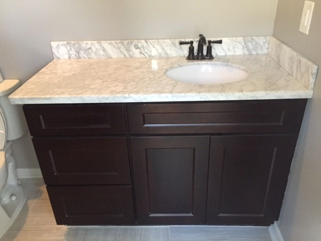 Esempio di una stanza da bagno minimal con ante in stile shaker, ante in legno bruno e top in marmo