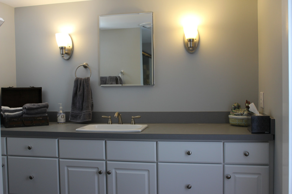 Bild på ett stort grå grått en-suite badrum, med luckor med infälld panel, grå skåp, en hörndusch, en toalettstol med hel cisternkåpa, vita väggar, klinkergolv i keramik, ett nedsänkt handfat, laminatbänkskiva, grått golv och dusch med skjutdörr