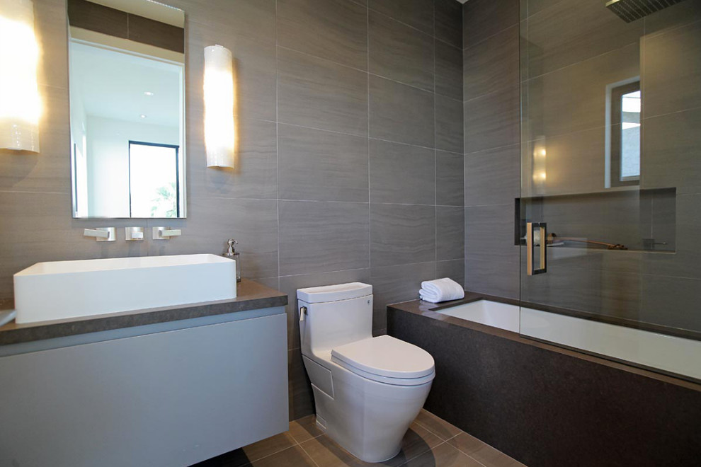 Esempio di una stanza da bagno con doccia moderna di medie dimensioni con ante lisce, ante grigie, vasca sottopiano, WC monopezzo, pareti grigie e lavabo a bacinella