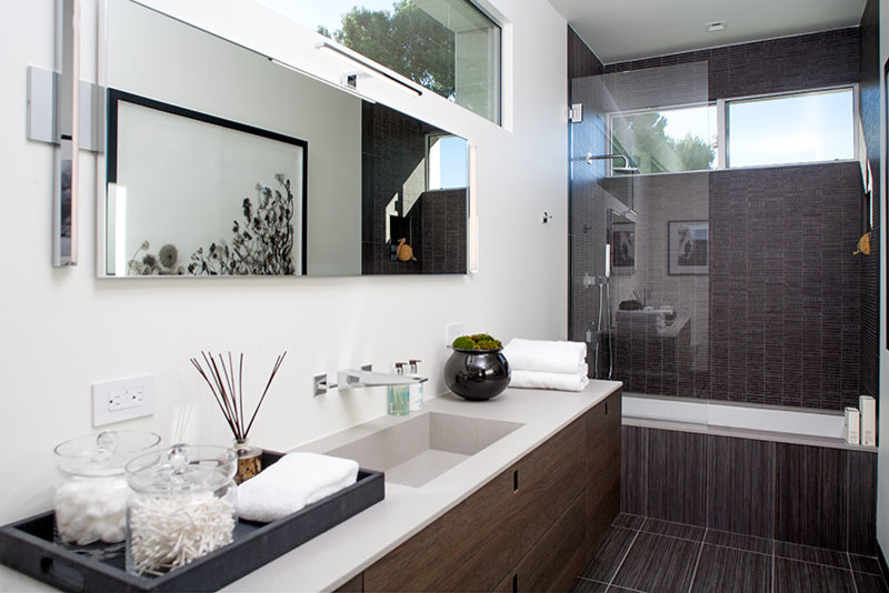 Inspiration for a mid-sized modern 3/4 white tile and stone slab ceramic tile bathroom remodel in Los Angeles with flat-panel cabinets, dark wood cabinets, a one-piece toilet, gray walls, a trough sink and solid surface countertops