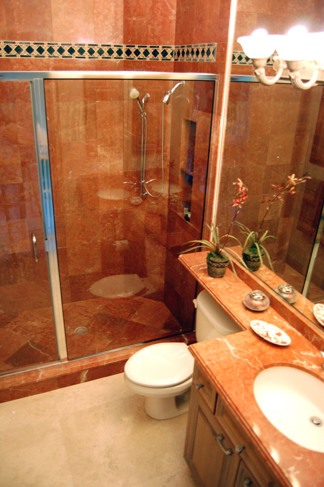 На фото: маленькая ванная комната в классическом стиле с врезной раковиной, фасадами с выступающей филенкой, фасадами цвета дерева среднего тона, душем в нише, унитазом-моноблоком, душевой кабиной, розовой плиткой, оранжевыми стенами, полом из травертина, мраморной столешницей, бежевым полом, душем с распашными дверями и мраморной плиткой для на участке и в саду с