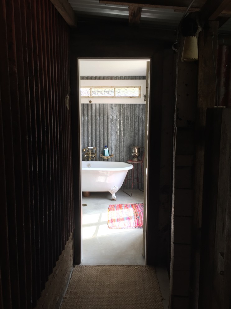 Cette image montre une petite douche en alcôve principale chalet avec un lavabo encastré, un placard en trompe-l'oeil, des portes de placard noires, une baignoire sur pieds, WC à poser, un mur gris et sol en béton ciré.