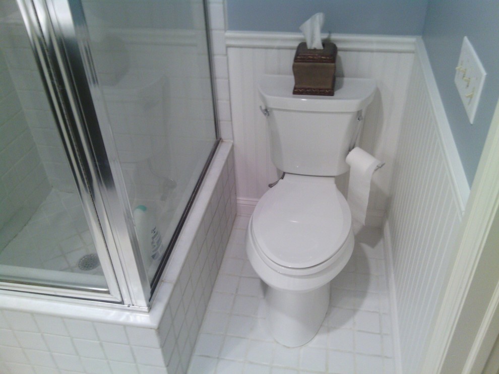 Cette image montre une salle de bain design de taille moyenne pour enfant avec un placard à porte shaker, des portes de placard noires, un plan de toilette en marbre, un carrelage blanc, des carreaux de céramique, une baignoire d'angle, un mur blanc et un sol en carrelage de céramique.