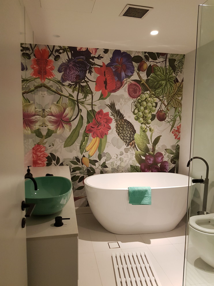 Cette image montre une salle de bain principale minimaliste de taille moyenne avec un placard à porte affleurante, des portes de placards vertess, une baignoire sur pieds, WC suspendus, un carrelage gris, un mur blanc, un plan de toilette en marbre, un sol blanc et un plan de toilette gris.