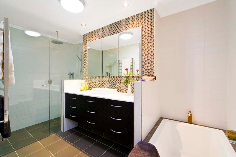 На фото: главная ванная комната среднего размера в современном стиле с фасадами островного типа, темными деревянными фасадами, мраморной столешницей, унитазом-моноблоком, разноцветной плиткой, стеклянной плиткой, белыми стенами и полом из керамической плитки с