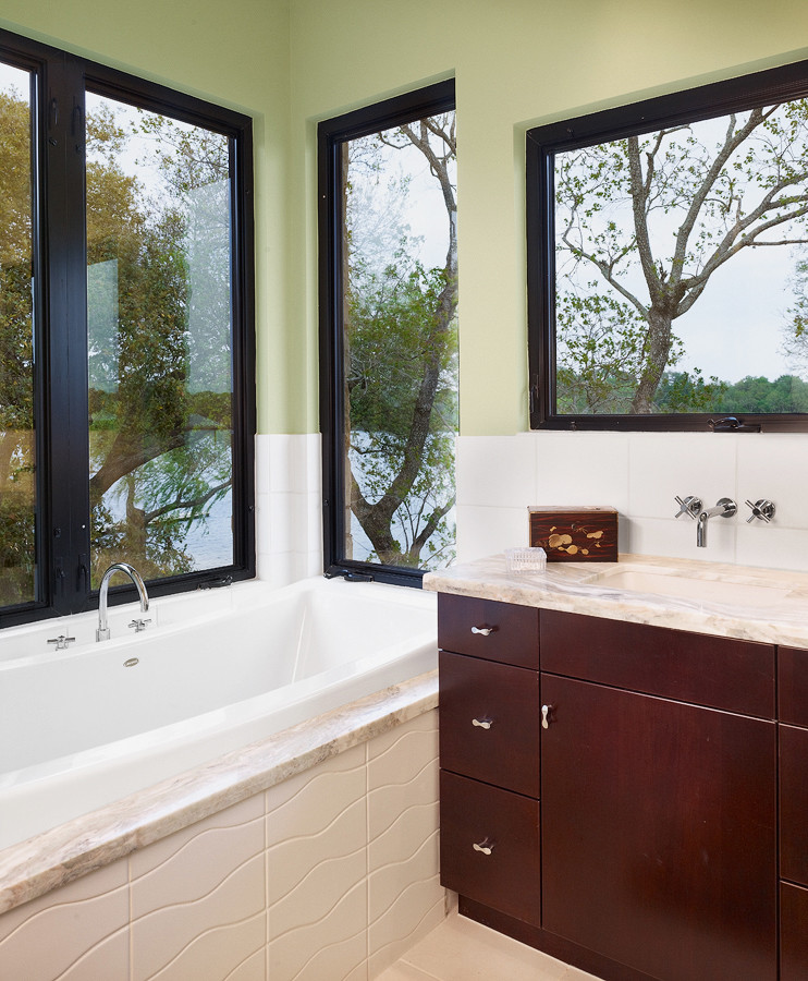 Photo of a medium sized modern ensuite bathroom in Austin with flat-panel cabinets, dark wood cabinets, white tiles, porcelain tiles, green walls, a submerged sink, a built-in bath and porcelain flooring.