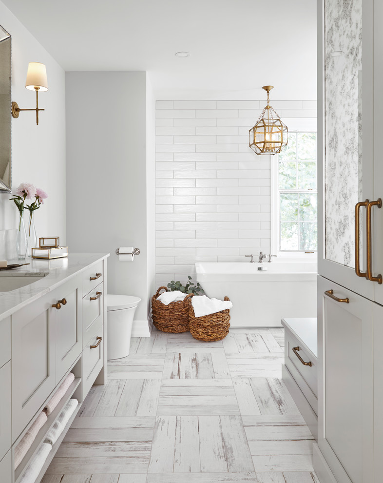 Inspiration for a classic bathroom in Toronto with shaker cabinets, white cabinets, a freestanding bath, a submerged sink and white floors.