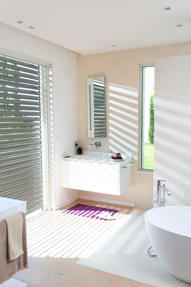 Imagen de cuarto de baño principal moderno de tamaño medio con puertas de armario blancas, bañera exenta y suelo beige