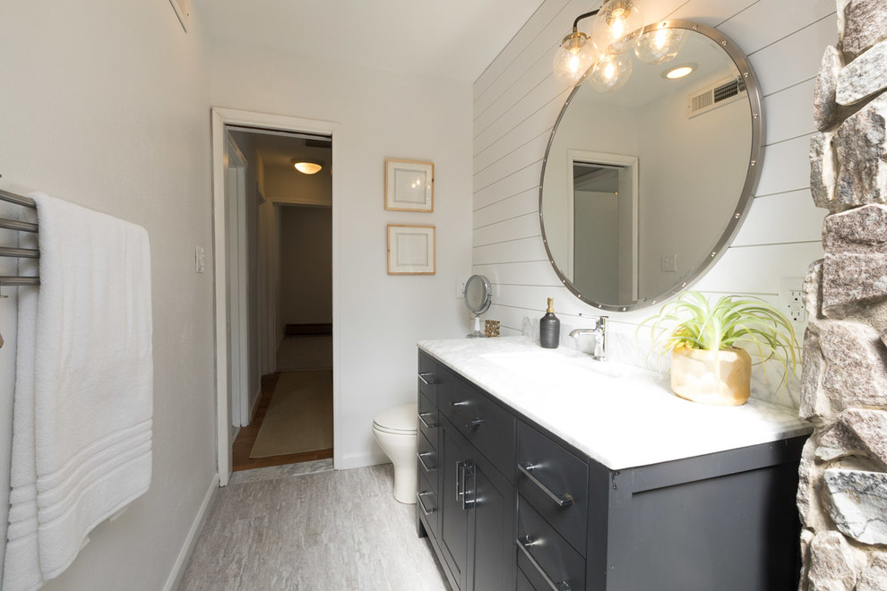 Eklektisk inredning av ett litet vit vitt en-suite badrum, med luckor med upphöjd panel, svarta skåp, ett platsbyggt badkar, en dusch i en alkov, en toalettstol med hel cisternkåpa, grå kakel, stenhäll, vita väggar, laminatgolv, ett konsol handfat, marmorbänkskiva, grått golv och med dusch som är öppen