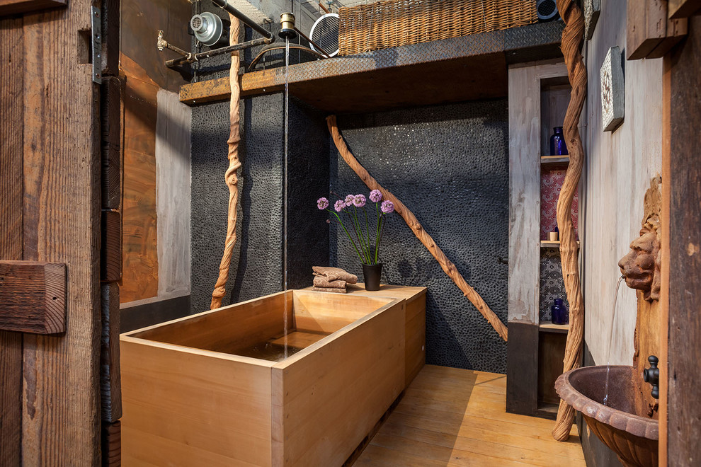 Idéer för industriella badrum, med ett japanskt badkar, en dusch/badkar-kombination, ljust trägolv, flerfärgade väggar och kakel i småsten