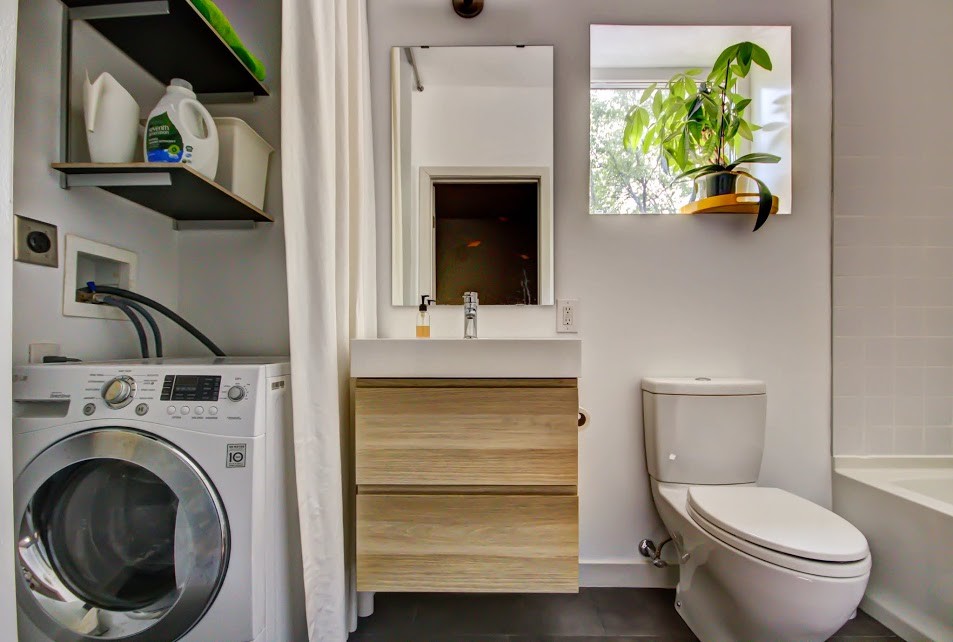 Пример оригинального дизайна: маленькая ванная комната со стиральной машиной в стиле модернизм с белыми стенами, полом из керамогранита, плоскими фасадами, светлыми деревянными фасадами, ванной в нише, душем над ванной, раздельным унитазом, бежевой плиткой, керамической плиткой, душевой кабиной, накладной раковиной, серым полом и открытым душем для на участке и в саду