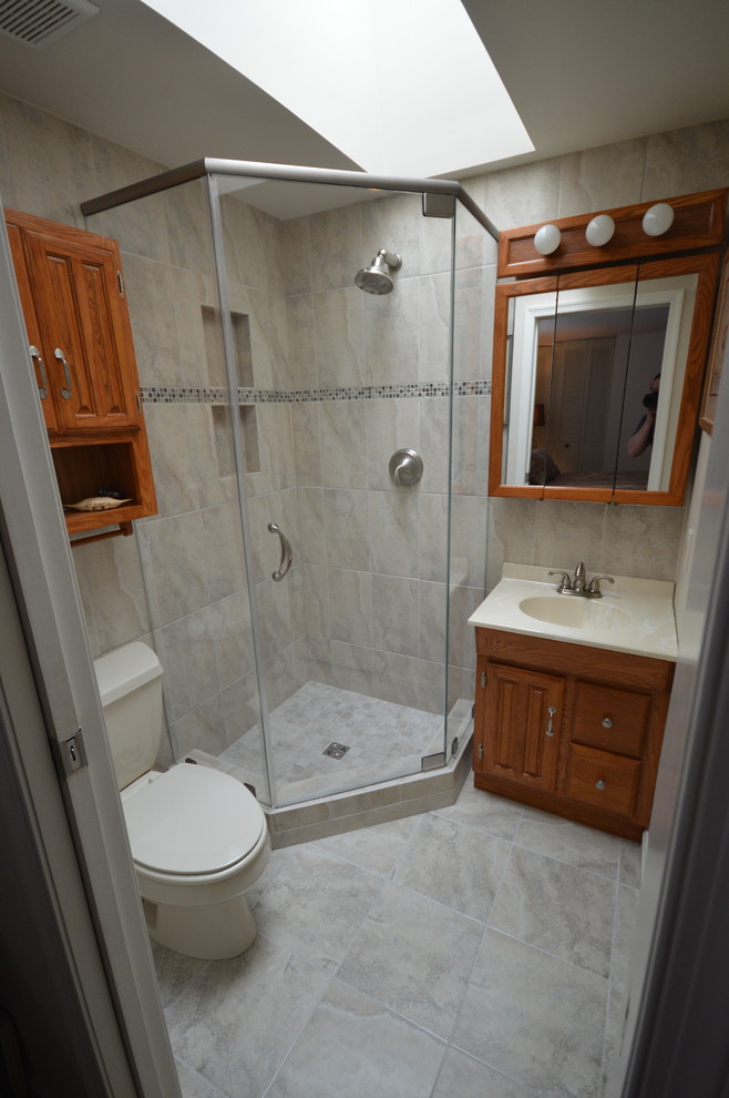 Foto di una piccola stanza da bagno stile americano con lavabo integrato, ante con bugna sagomata, ante in legno scuro, pareti grigie e pavimento in gres porcellanato