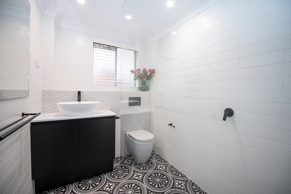 Foto på ett litet vintage vit badrum, med släta luckor, en vägghängd toalettstol, svart och vit kakel, porslinskakel, vita väggar, klinkergolv i terrakotta, ett fristående handfat, bänkskiva i kvarts, svart golv och med dusch som är öppen