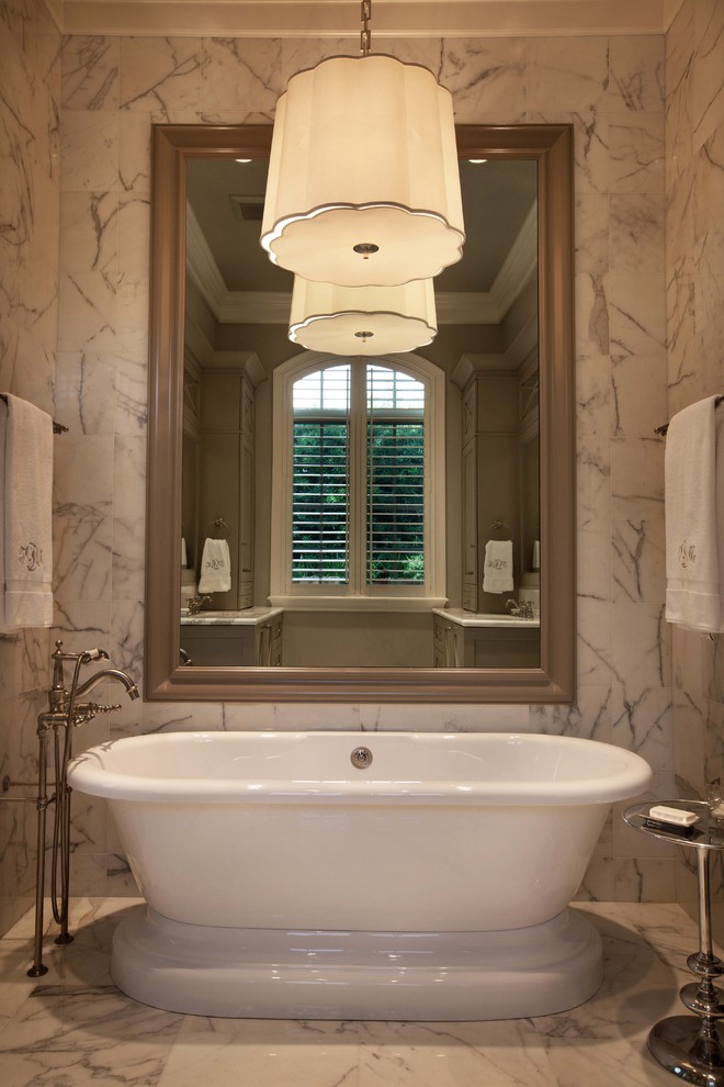 На фото: большая главная ванная комната: освещение в стиле фьюжн с отдельно стоящей ванной и мраморным полом с