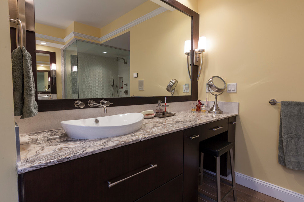 Exempel på ett stort modernt en-suite badrum, med ett fristående handfat, släta luckor, skåp i mörkt trä, bänkskiva i onyx, ett fristående badkar, en dubbeldusch, en bidé, beige kakel, porslinskakel, gula väggar och klinkergolv i porslin
