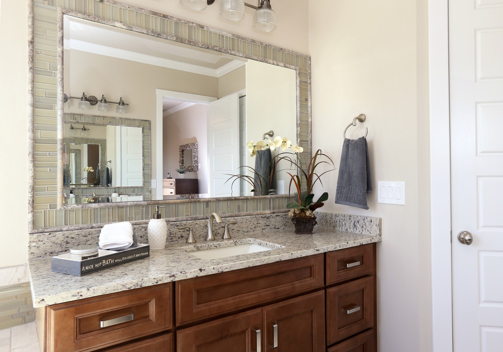 Idée de décoration pour une salle de bain principale ethnique en bois brun de taille moyenne avec un lavabo encastré, un placard avec porte à panneau encastré, un plan de toilette en granite, un carrelage gris, un carrelage en pâte de verre, un mur gris et un sol en carrelage de porcelaine.