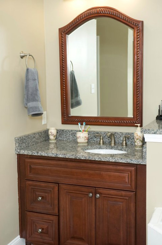 Ejemplo de cuarto de baño pequeño con lavabo bajoencimera, armarios con paneles empotrados, puertas de armario de madera oscura, encimera de granito y paredes beige