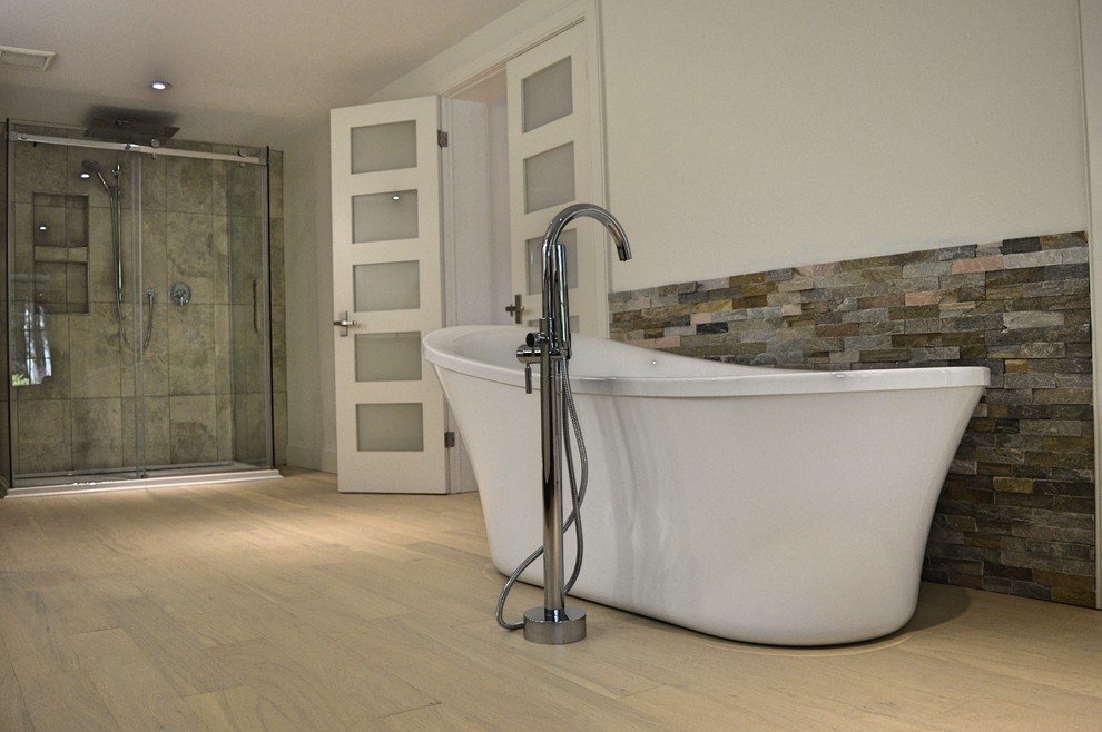 Modern inredning av ett stort en-suite badrum, med ett fristående badkar, en dusch i en alkov, vita väggar och ljust trägolv